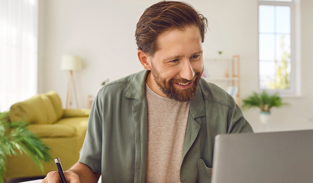 Smiling man working on laptop - Is lifelong learning the key to personal and professional growth